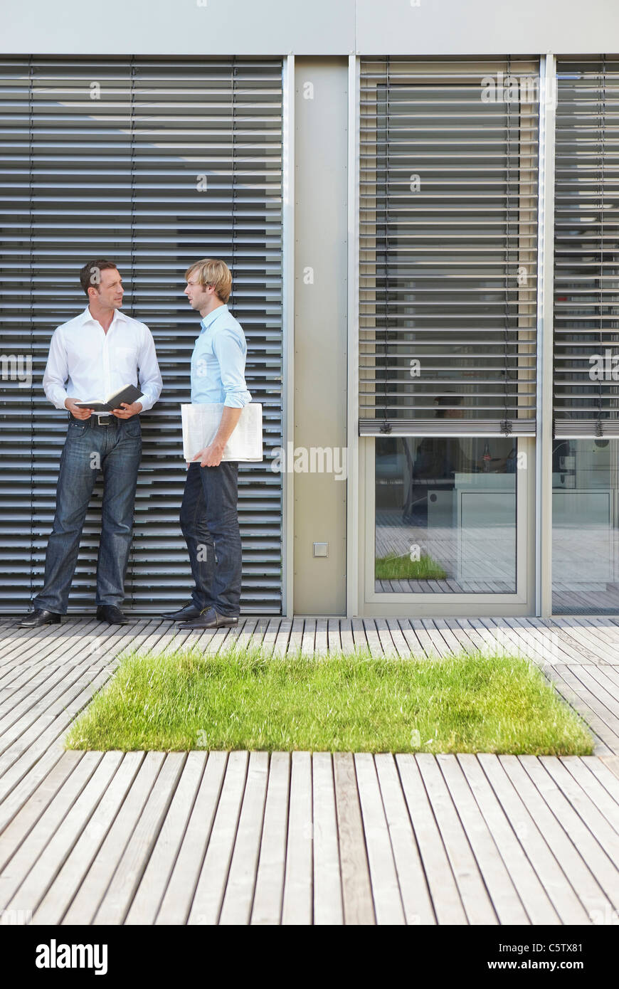 Germany, Cologne, Two businessmen in front of office building talking