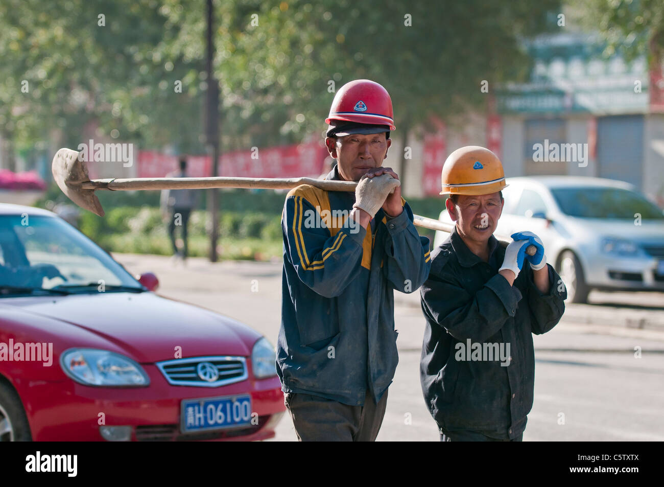 Laborers carry shovels on way to work, Dulan, Qinghai Province, China Stock Photo