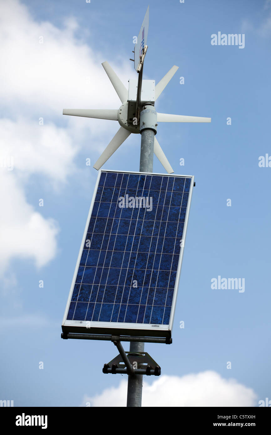 A solar panel and small wind turbine against a blu sky. Stock Photo