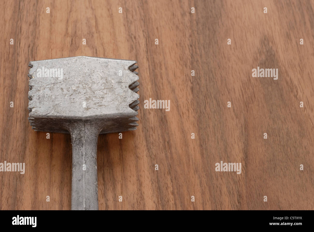 Meat tenderizer on wooden table, elevated view Stock Photo
