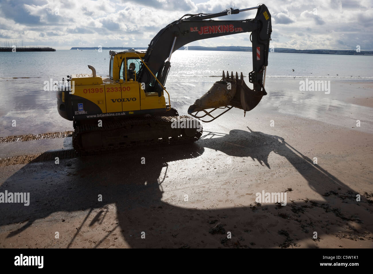 Large Volvo digger JCB style with shadow on the beach in Torquay Stock Photo