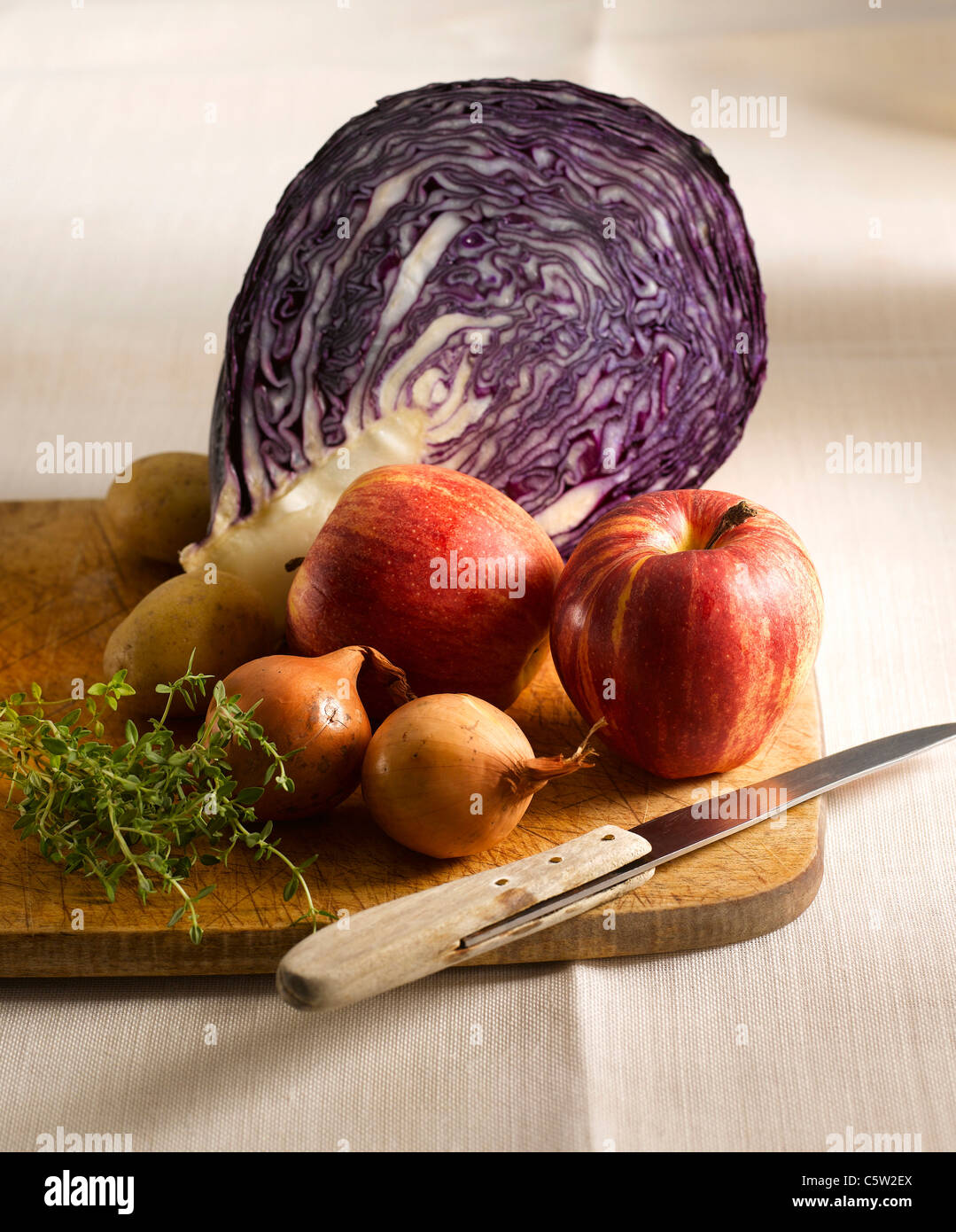 Red cabbage, apples, potatoes, thyme and onions on chopping board Stock