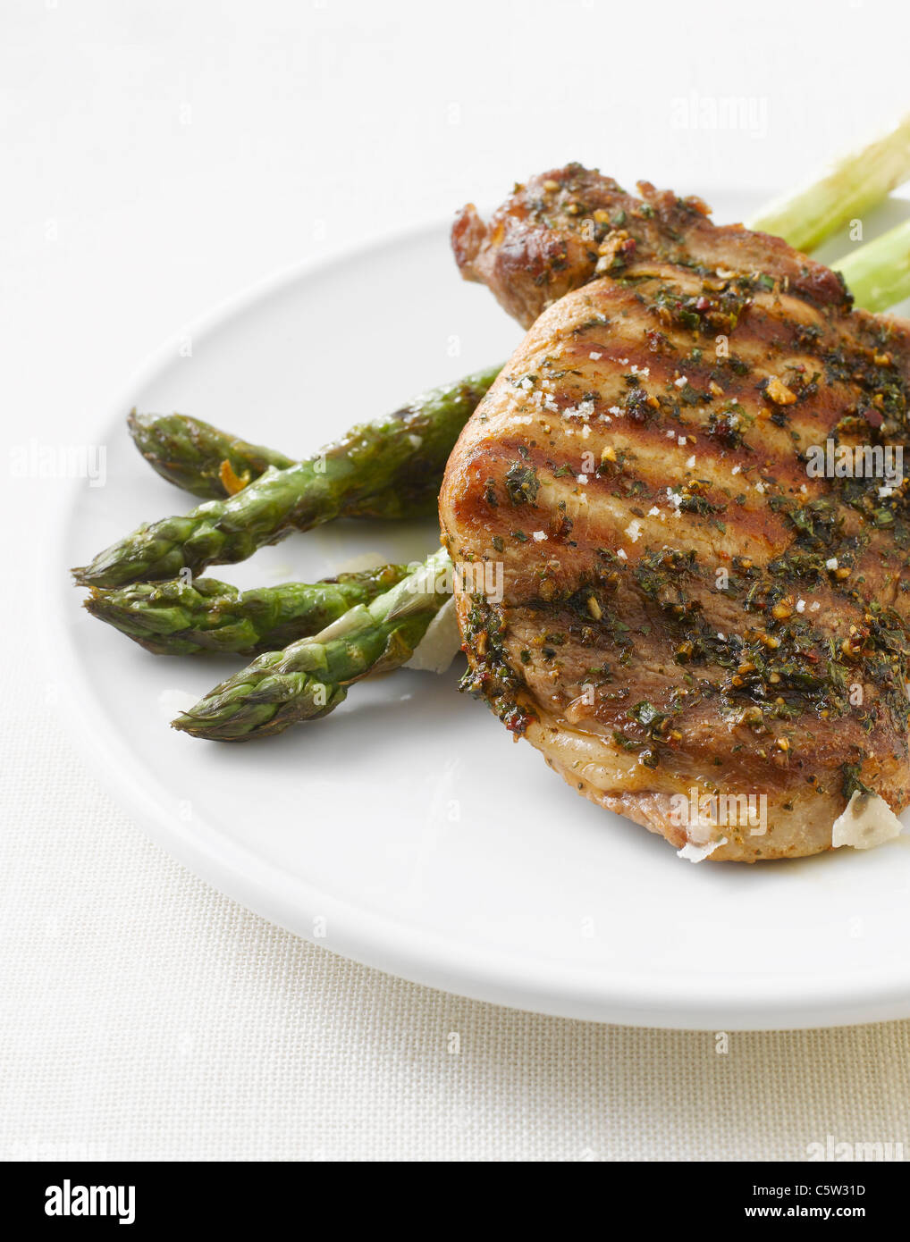 Grilled pork chop and green asparagus on plate Stock Photo