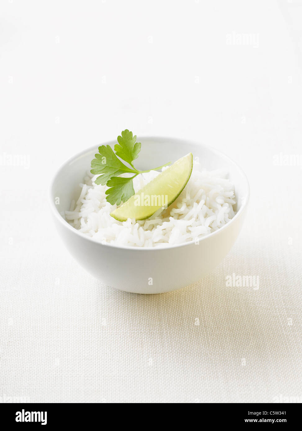 Boiled rice, garnished with parsley and lime in bowl Stock Photo
