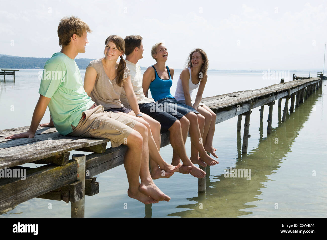 Germany, Bavaria, Ammersee, Young people relaxing on jetty Stock Photo