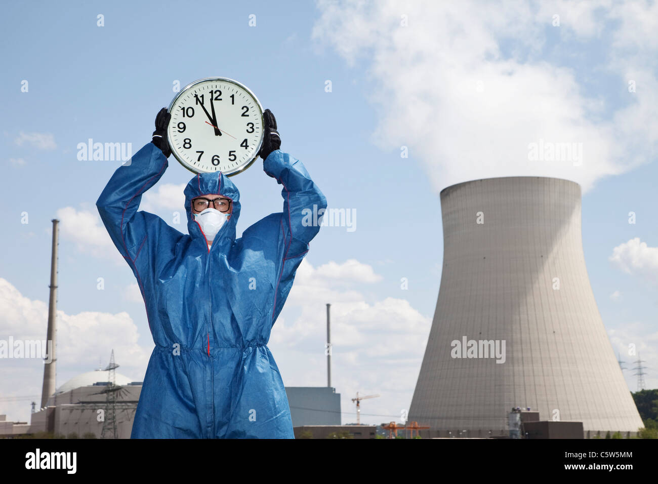 Germany, Bavaria, Unterahrain, Man in protective workwear holding clock at AKW Isar Stock Photo