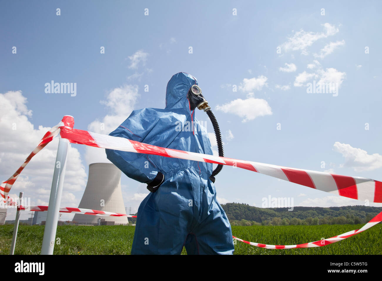 Germany, Bavaria, Unterahrain, Man with protective workwear standing in field at AKW Isar and cordon tape in foreground Stock Photo
