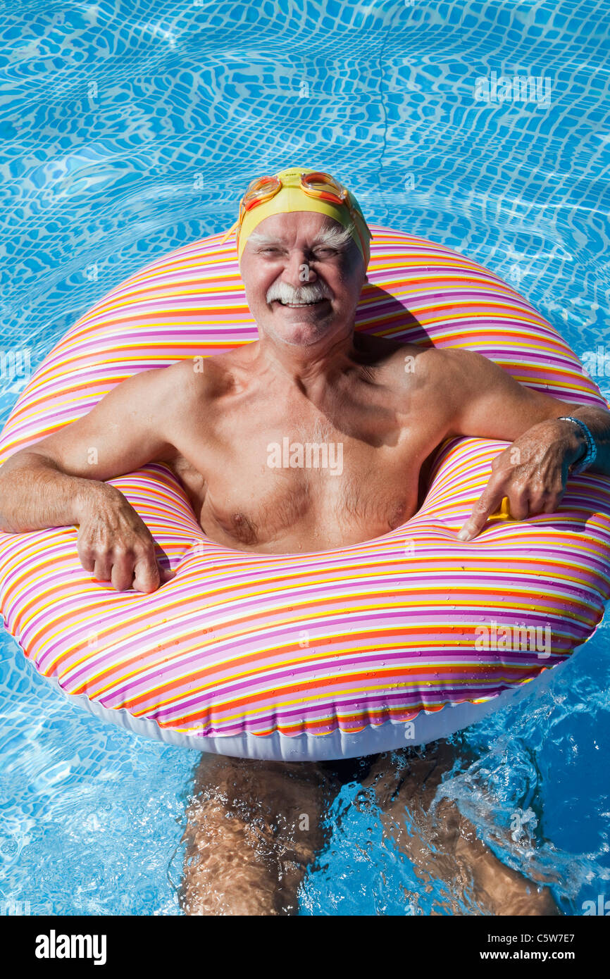 Austria, Senior man with floating tire in swimming pool, smiling, portrait Stock Photo