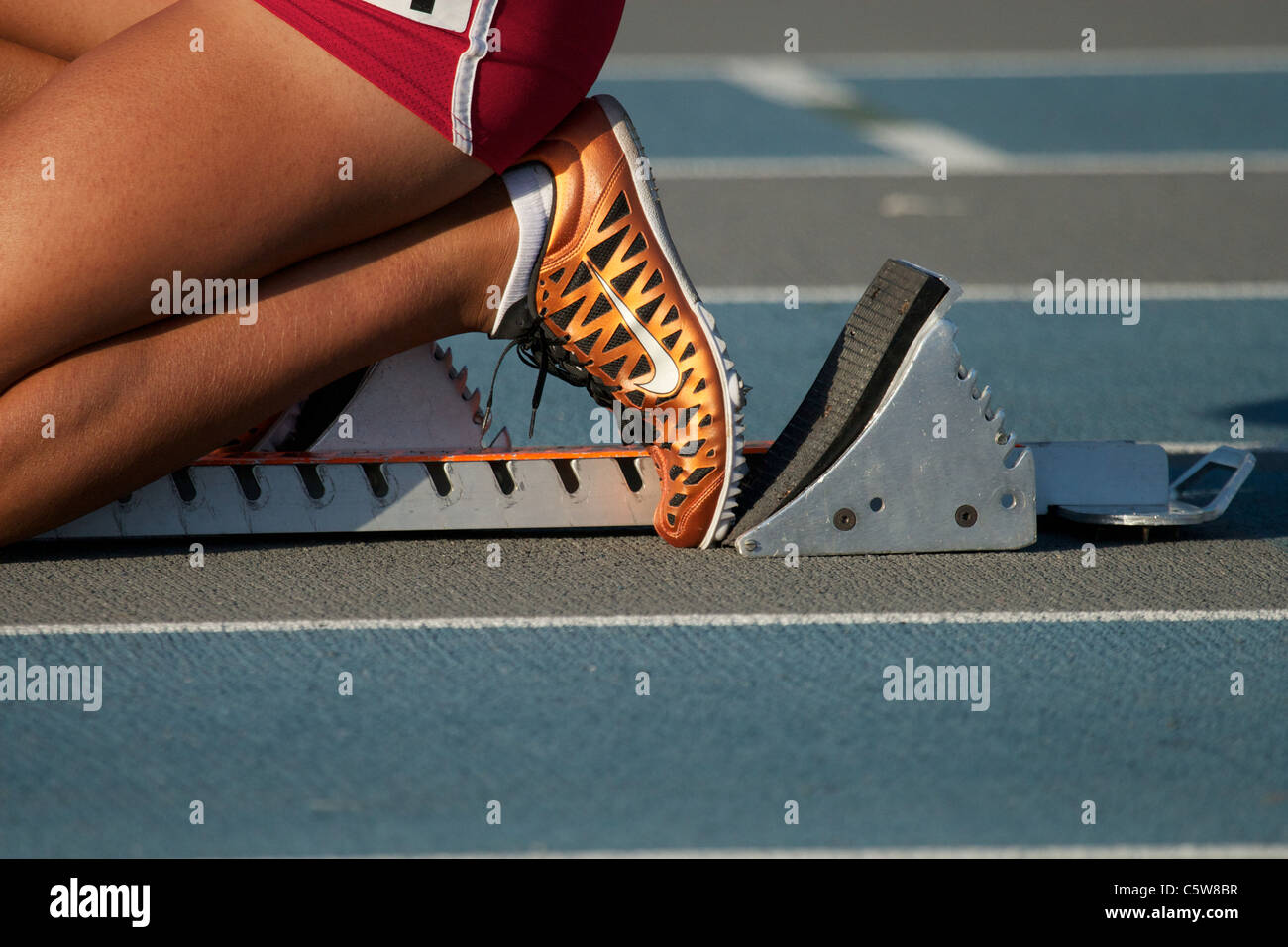 teenage girl in starting blocks on a blue and gray  running track Stock Photo