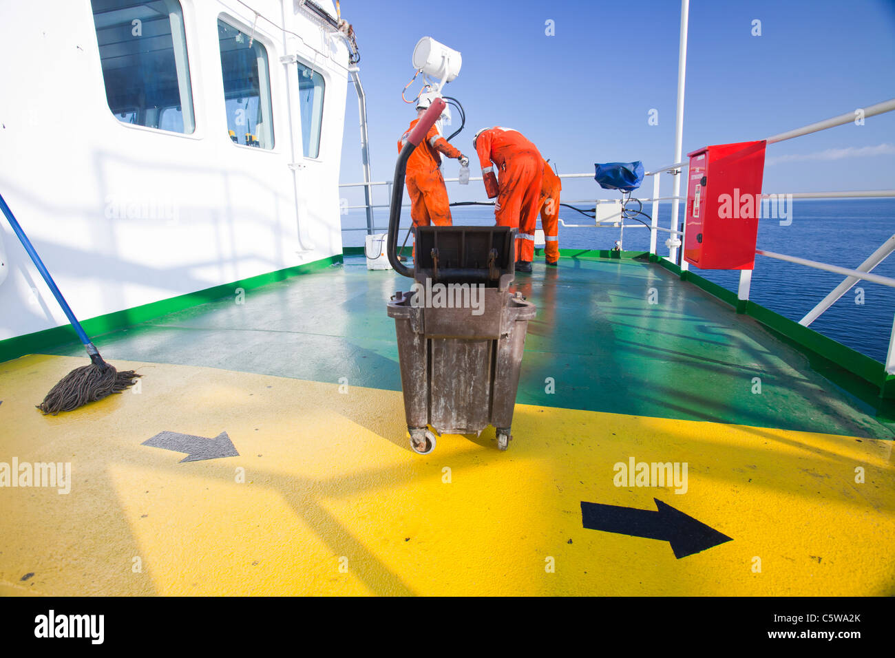 Workers scrub grease off the deck of the jack up barge, Kraken. The grease is blown off the legs