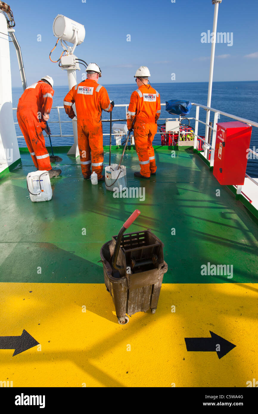 Workers scrub grease off the deck of the jack up barge, Kraken. The grease is blown off the legs