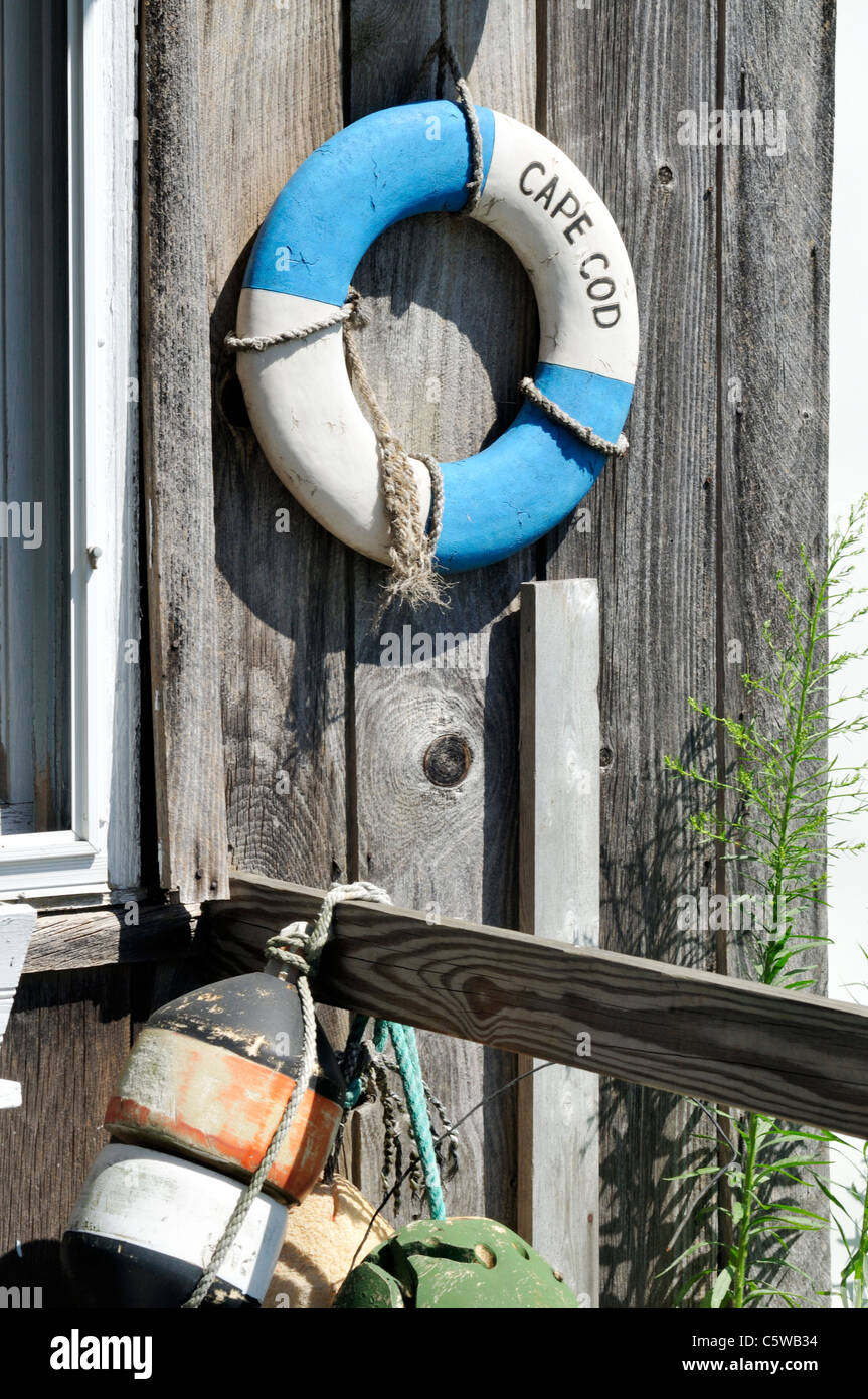 Classic Cape Cod scene with lobster buoys and classic life ring on weathered wood of exterior of building, USA Stock Photo