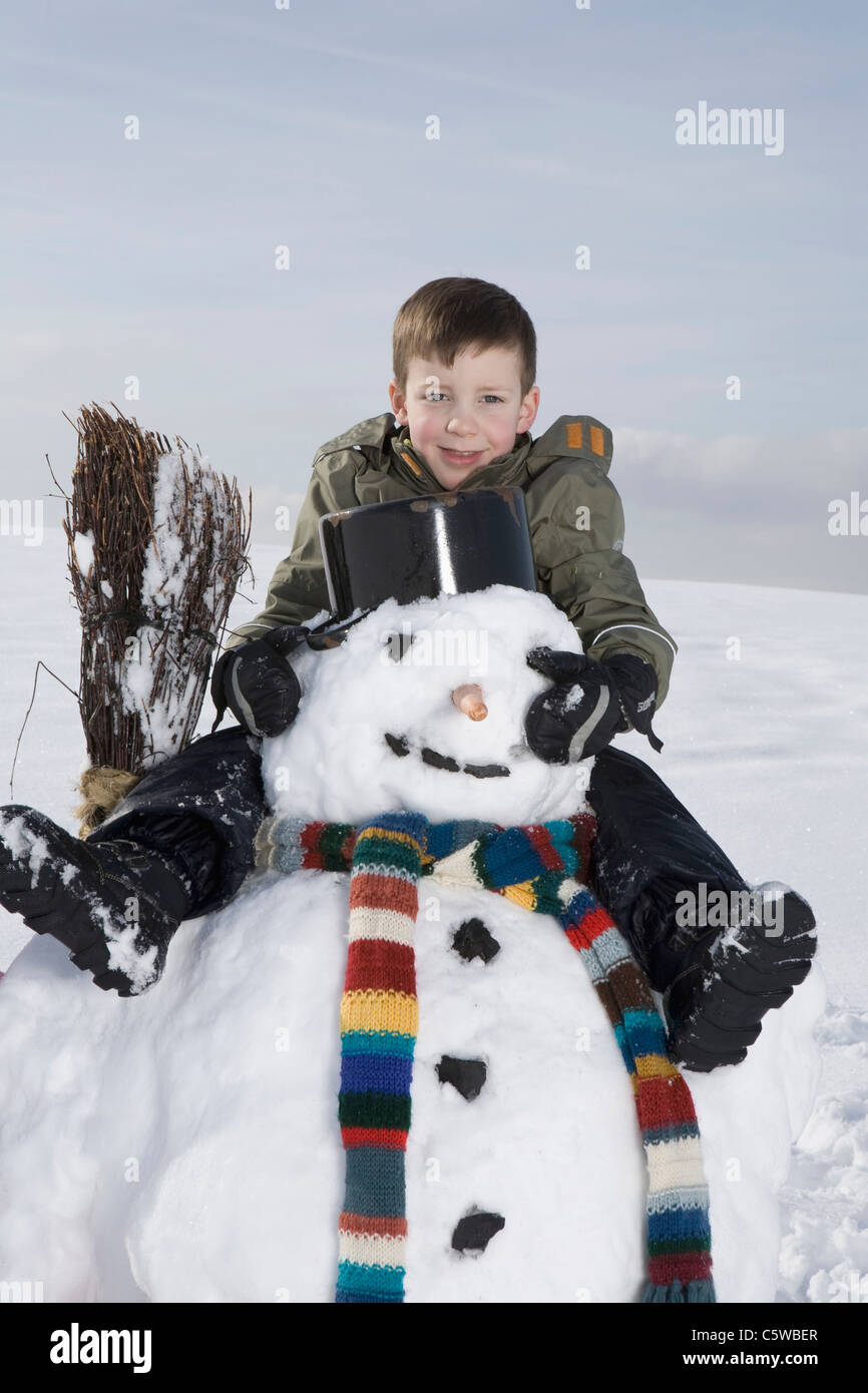 Germany, Bavaria, Munich, Boy (8-9) sitting on snowman, portrait Stock Photo