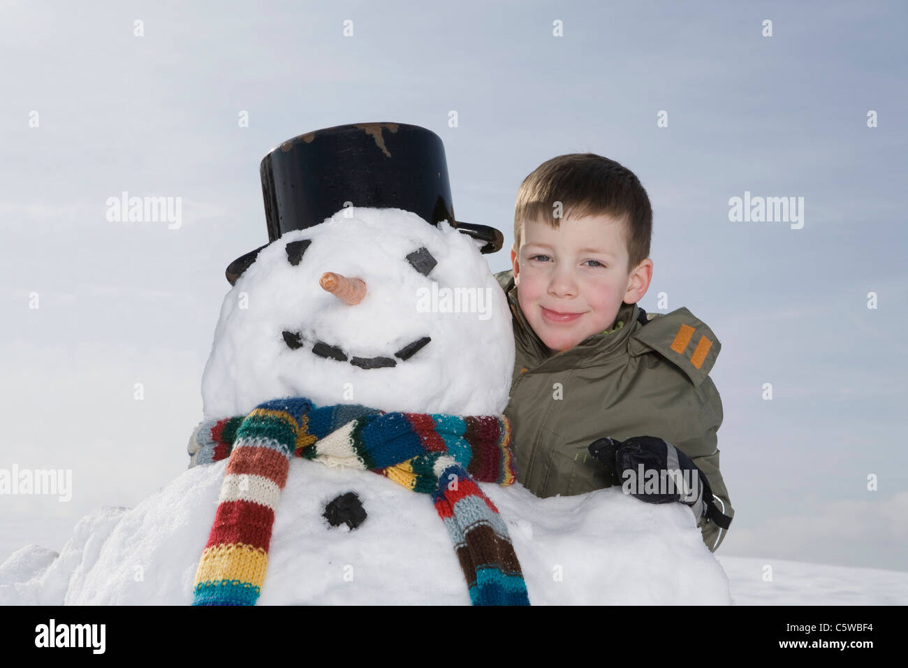 Germany, Bavaria, Munich, Boy (8-9) standing next to snowman, portrait Stock Photo