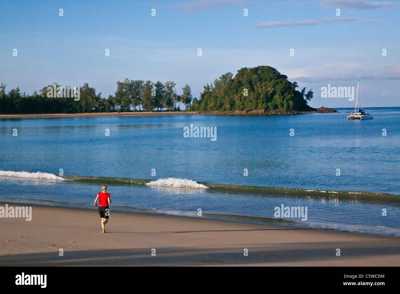 A jogger and catamaran on KOH PHRA THONG ISLAND near the Golden Buddha resort THAILAND Stock