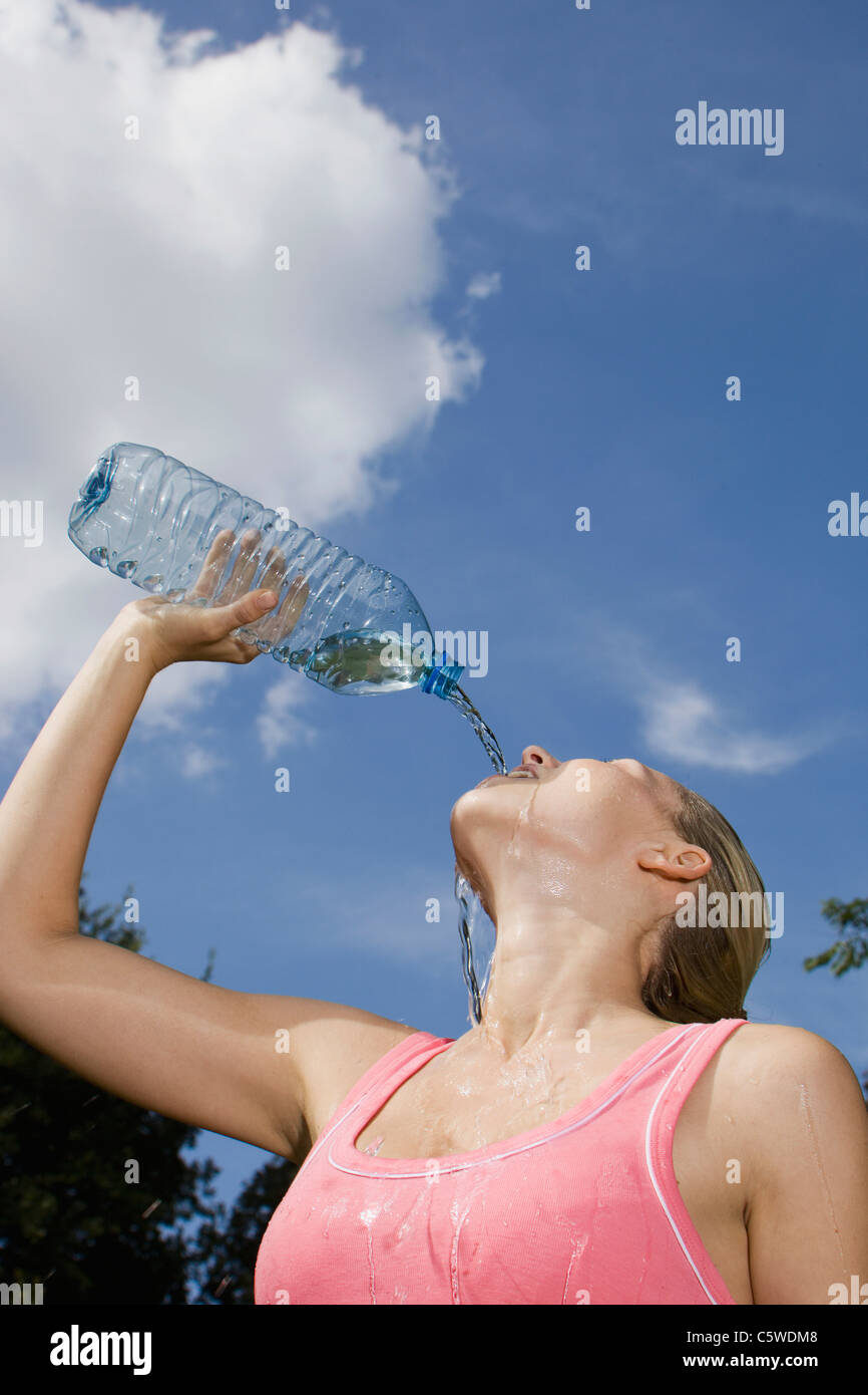 Germany, Berlin, Young woman pouring water over face, portrait Stock Photo
