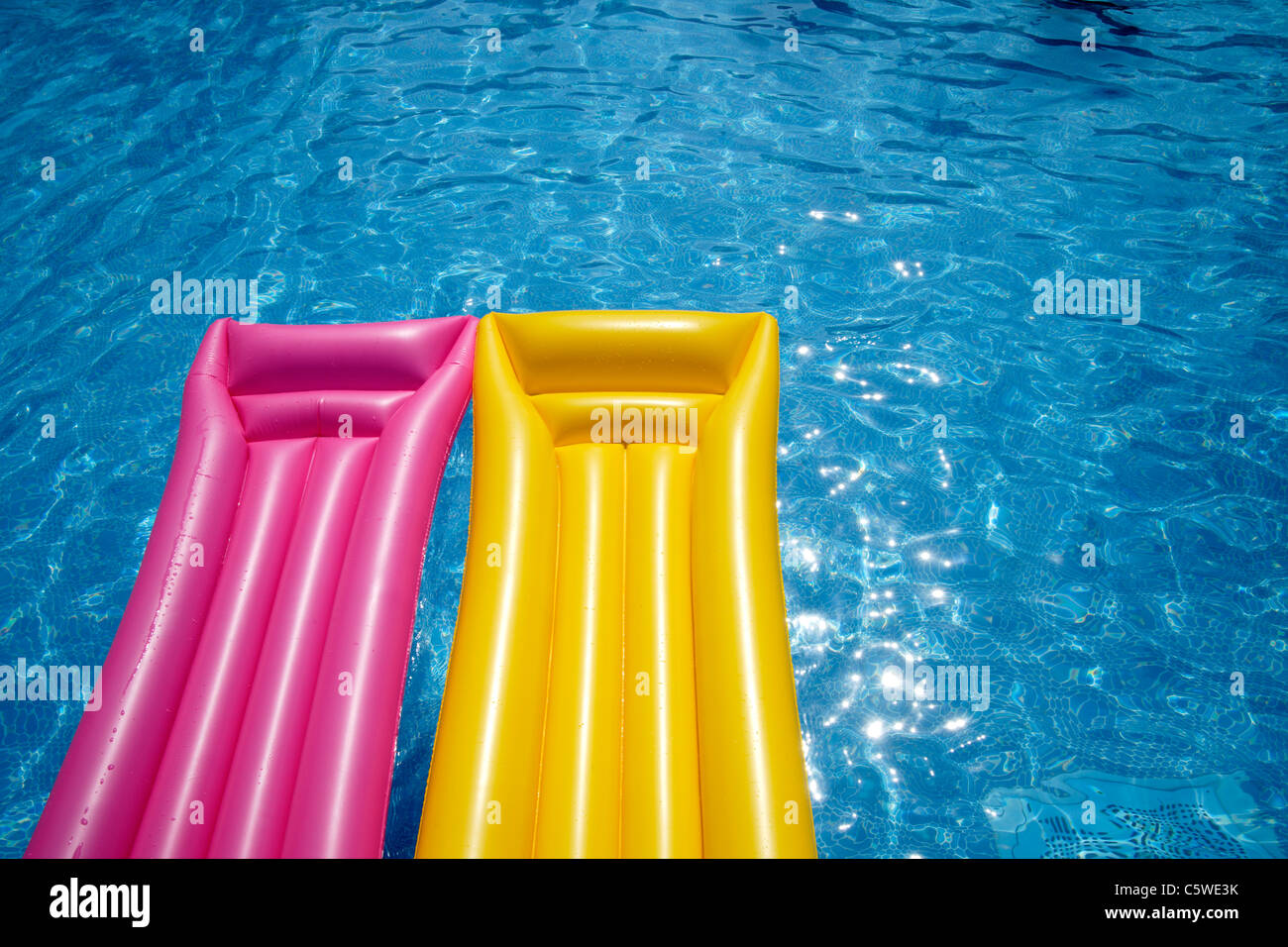 Two airbeds floating in pool, elevated view Stock Photo