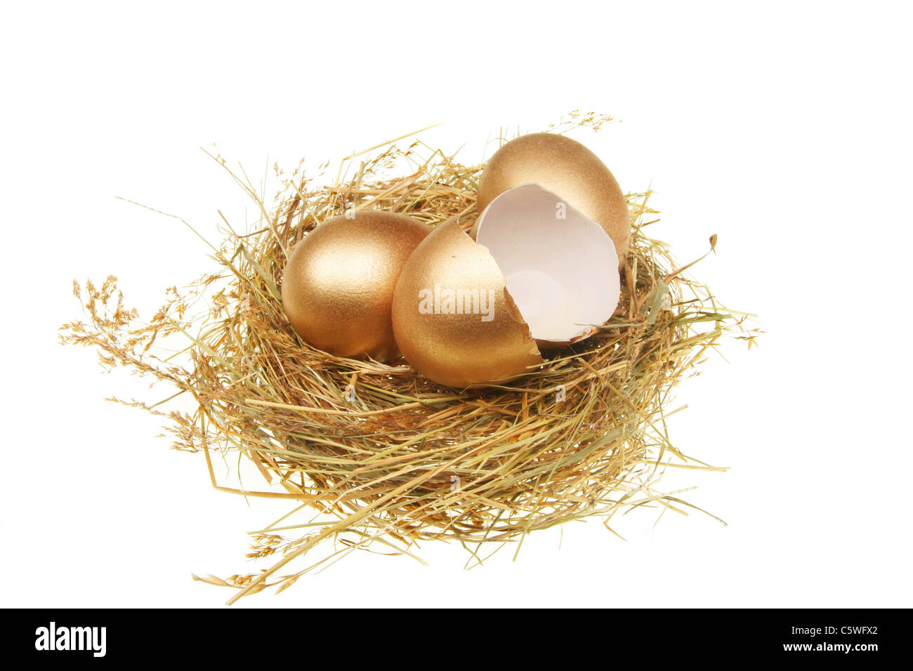 Two whole and one broken golden eggs in a straw nest Stock Photo