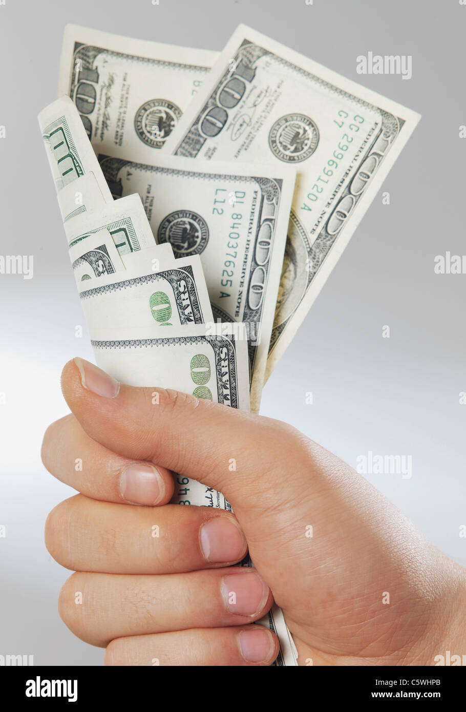 Close up of human hand gripping dollar notes against white background Stock Photo