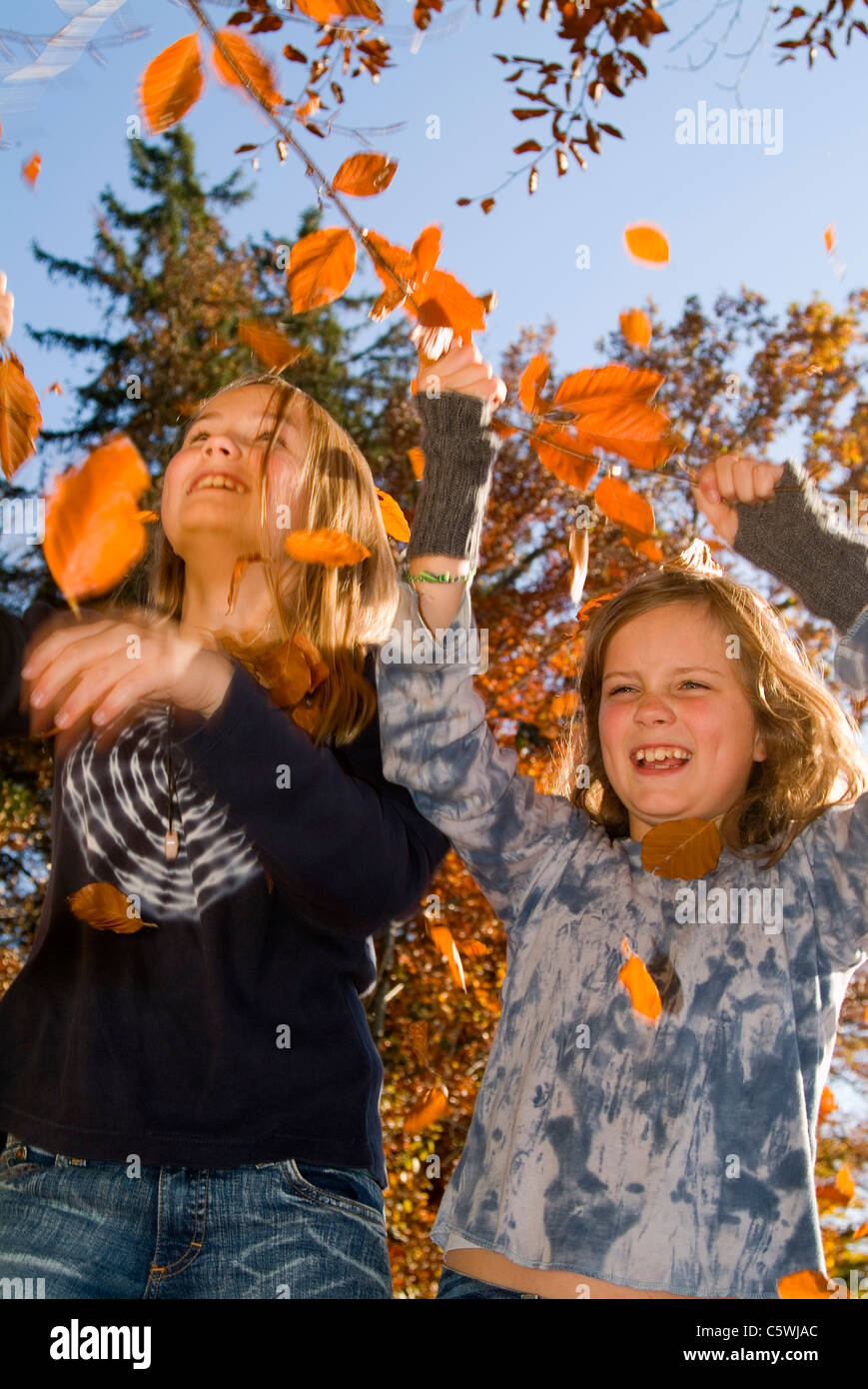 Two girls playing with autumn leaves Stock Photo - Alamy