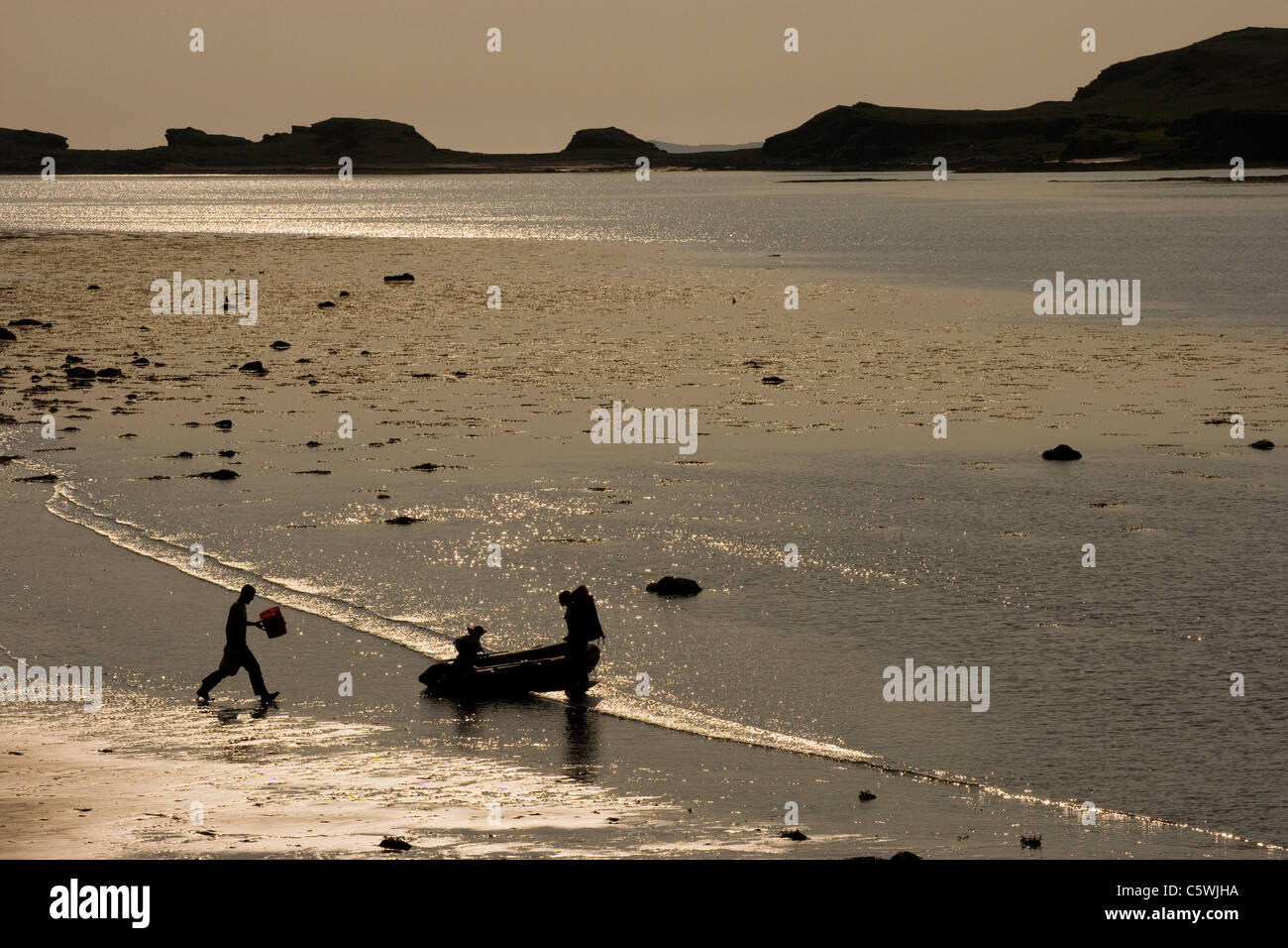 Family on beach launching small boat, Isle of Mull, Scotland, Great Britain. Stock Photo