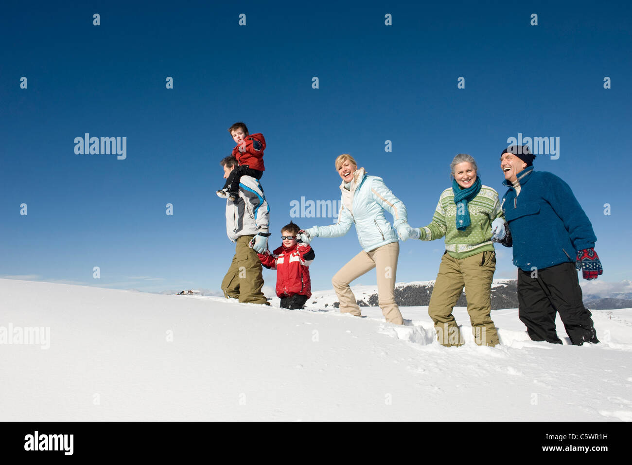 Italy, South Tyrol, Seiseralm, Family Walking in the Snow Stock Photo