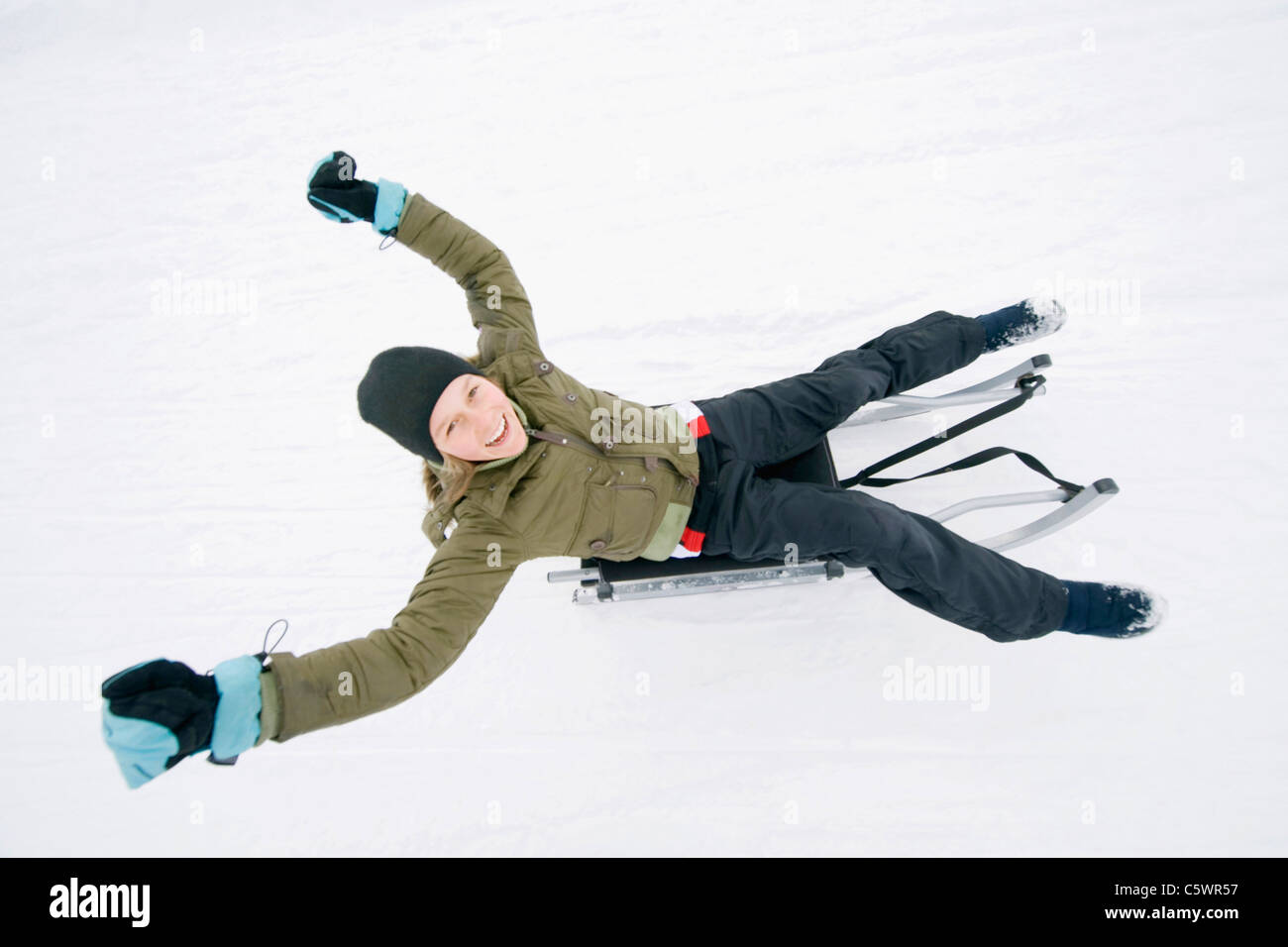 Italy, South Tyrol, Seiseralm, Girl (12-13) sledding downhill, portrait Stock Photo
