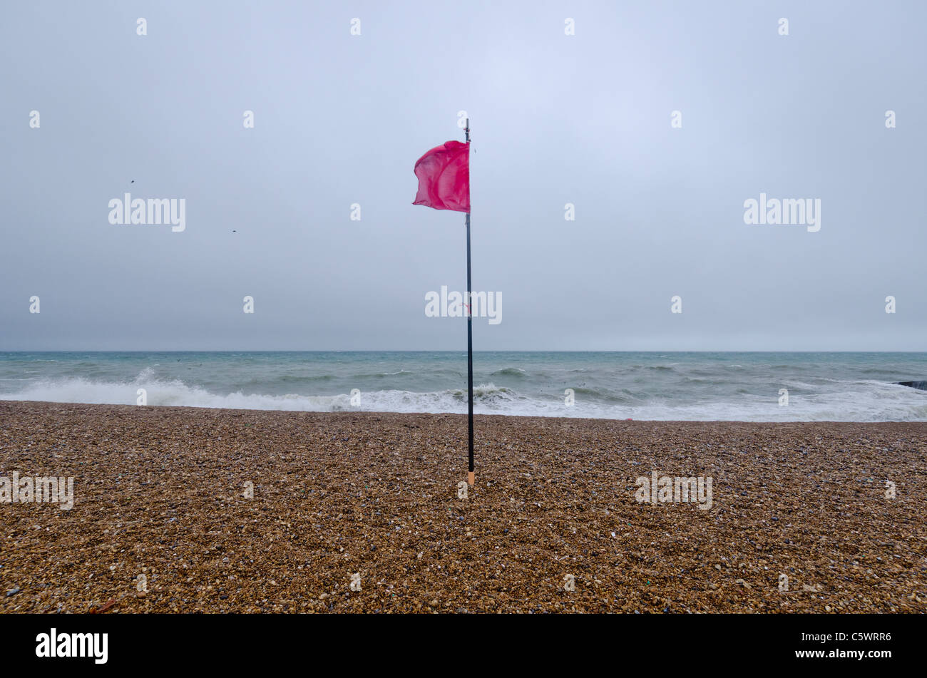 A man braves the stormy weather at Saltdean, ast East Sussex, promenade, as waves hit the breakwater. Stock Photo