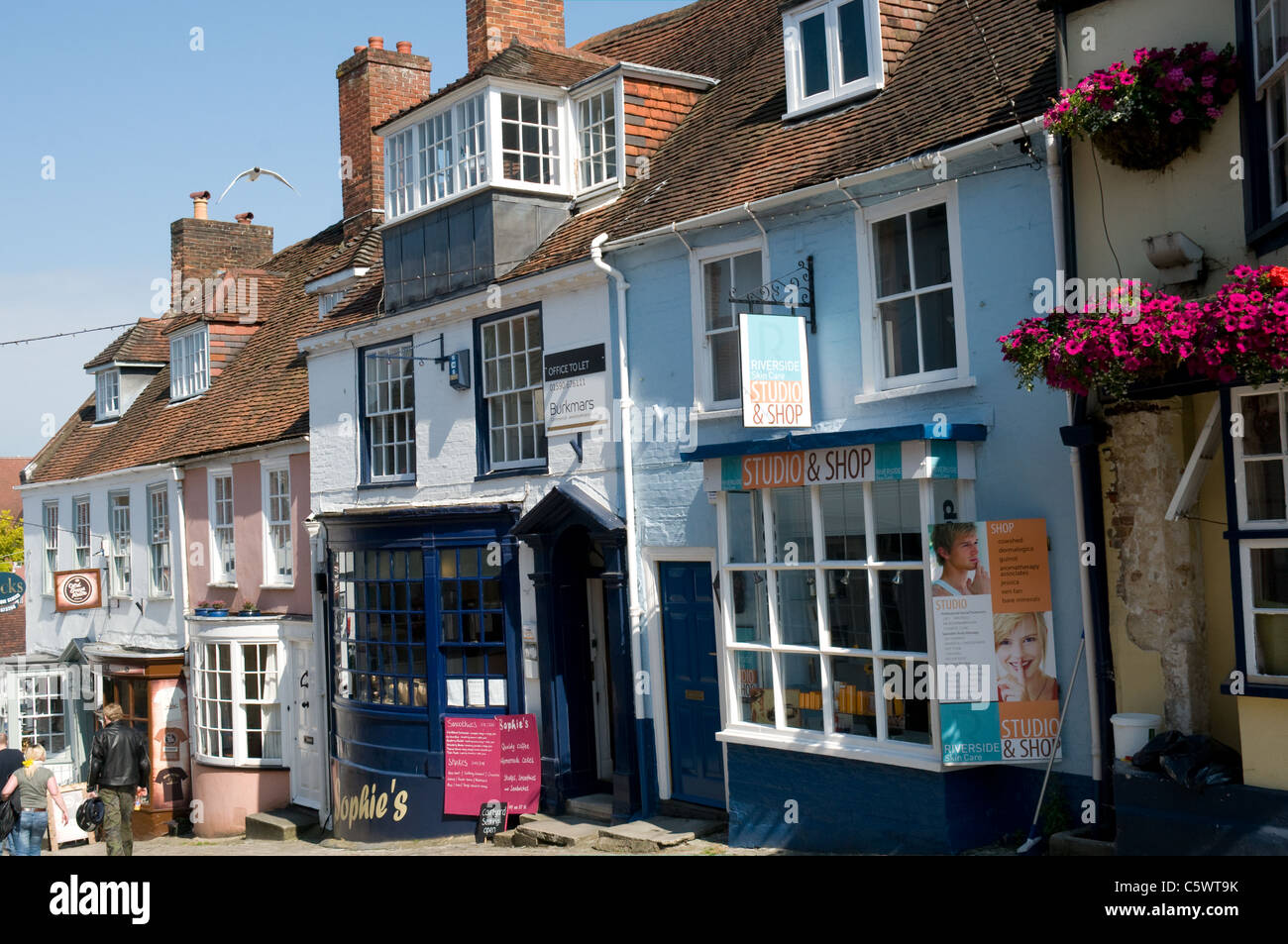 A row of old shops line the southern side of the sharply descending Quay Hill in Lymington, Hampshire Stock Photo