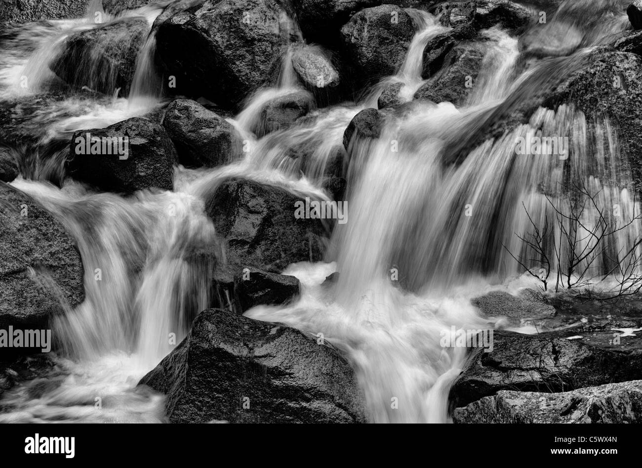 Black and white soft focus cascading water over large rocks Stock Photo