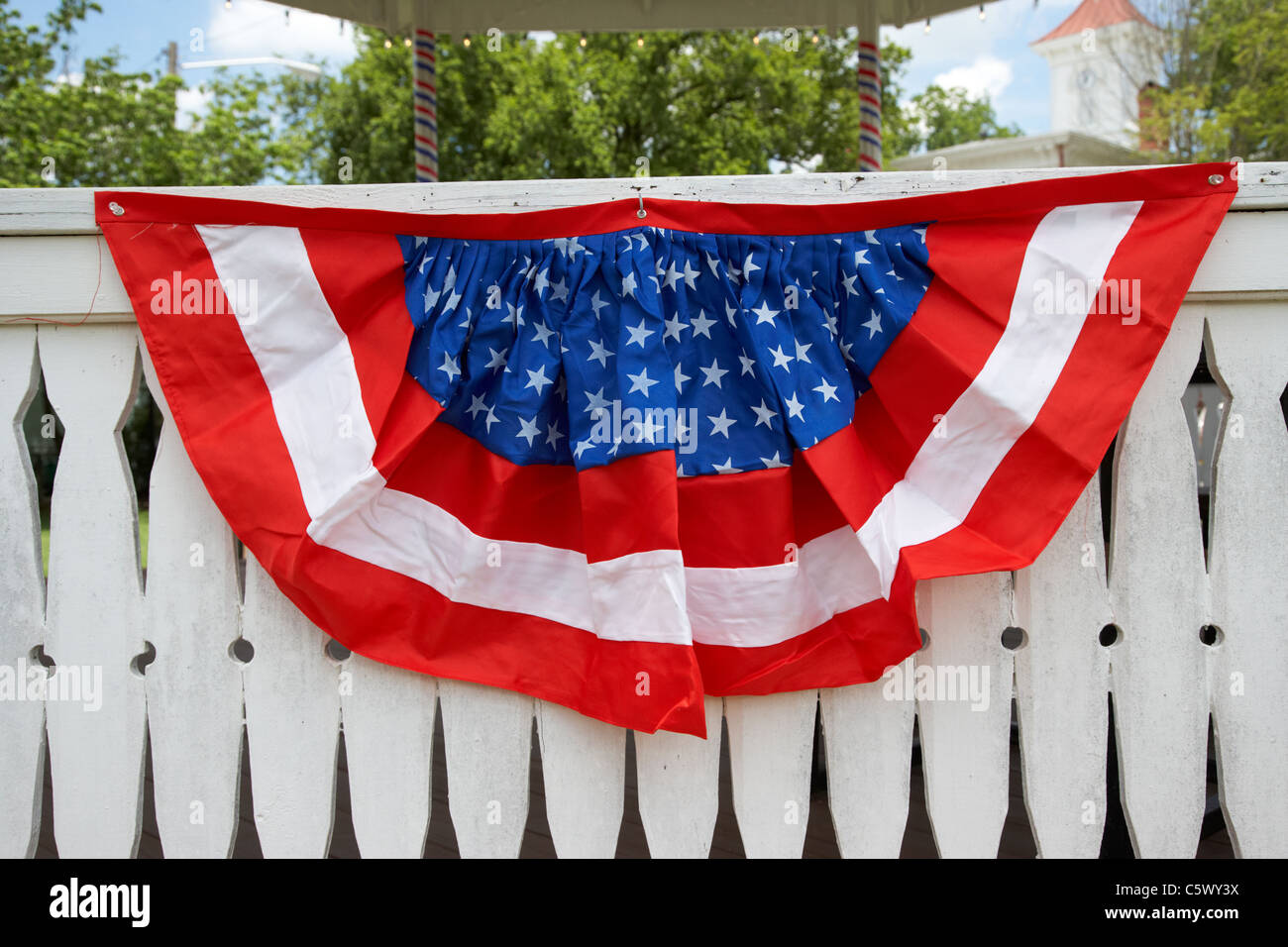 red white and blue american flag bunting put out on white fence for the