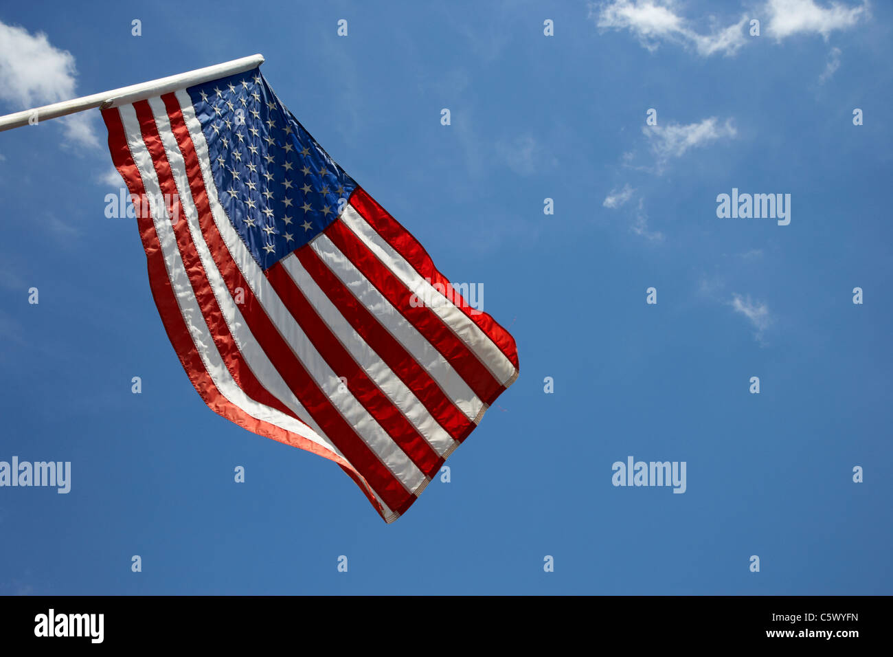 us american flag on flagpole against blue cloudy sky usa Stock Photo