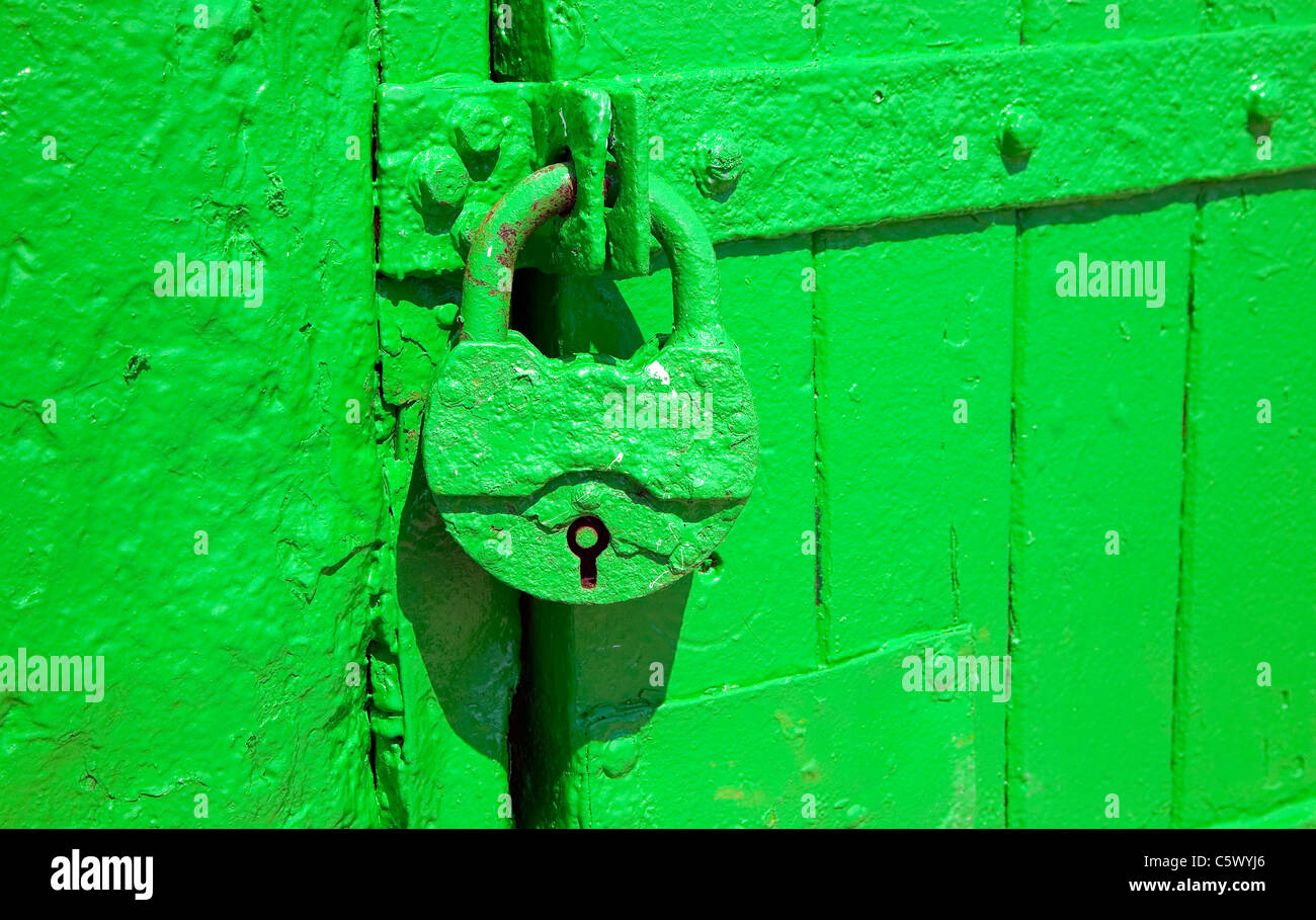 Green metal lock is hanging to protect entrance through doors Stock Photo