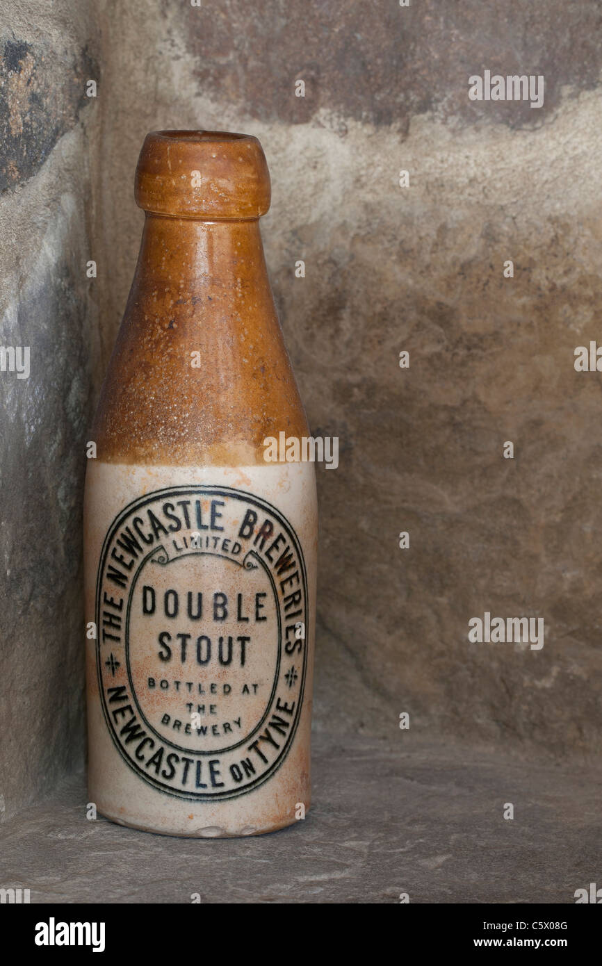 Antique Newcastle Breweries double stout brown ale ceramic bottle against a stone wall Stock