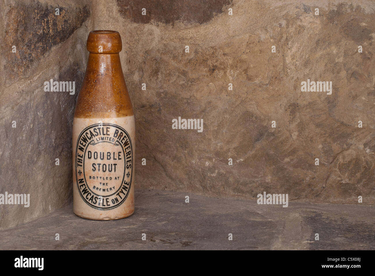 Antique Newcastle Breweries double stout brown ale ceramic bottle against a stone wall Stock Photo