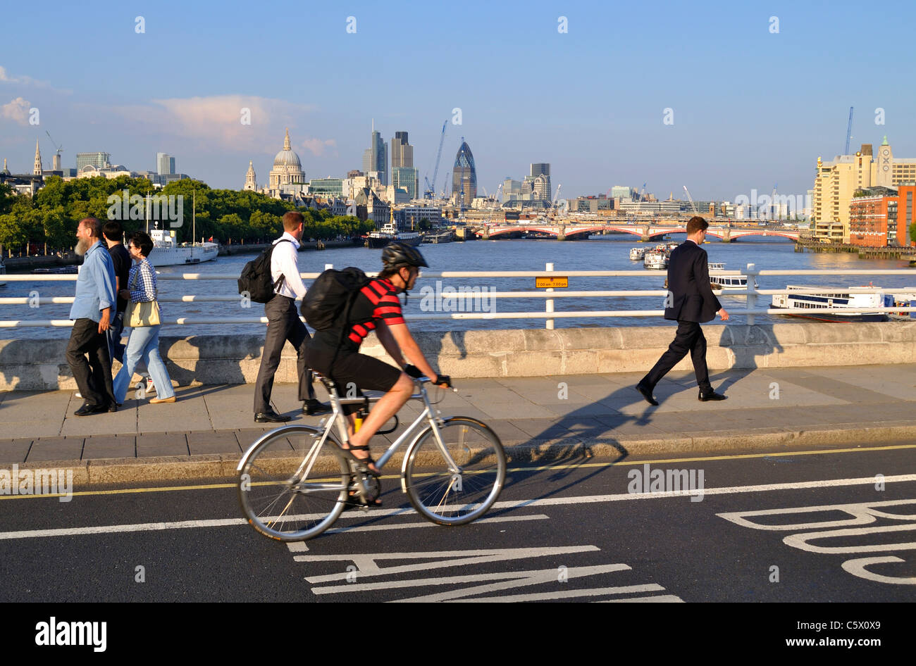 Pedestrians and a cyclist crossing Waterloo Bridge over the River Thames in the City of London Stock Photo
