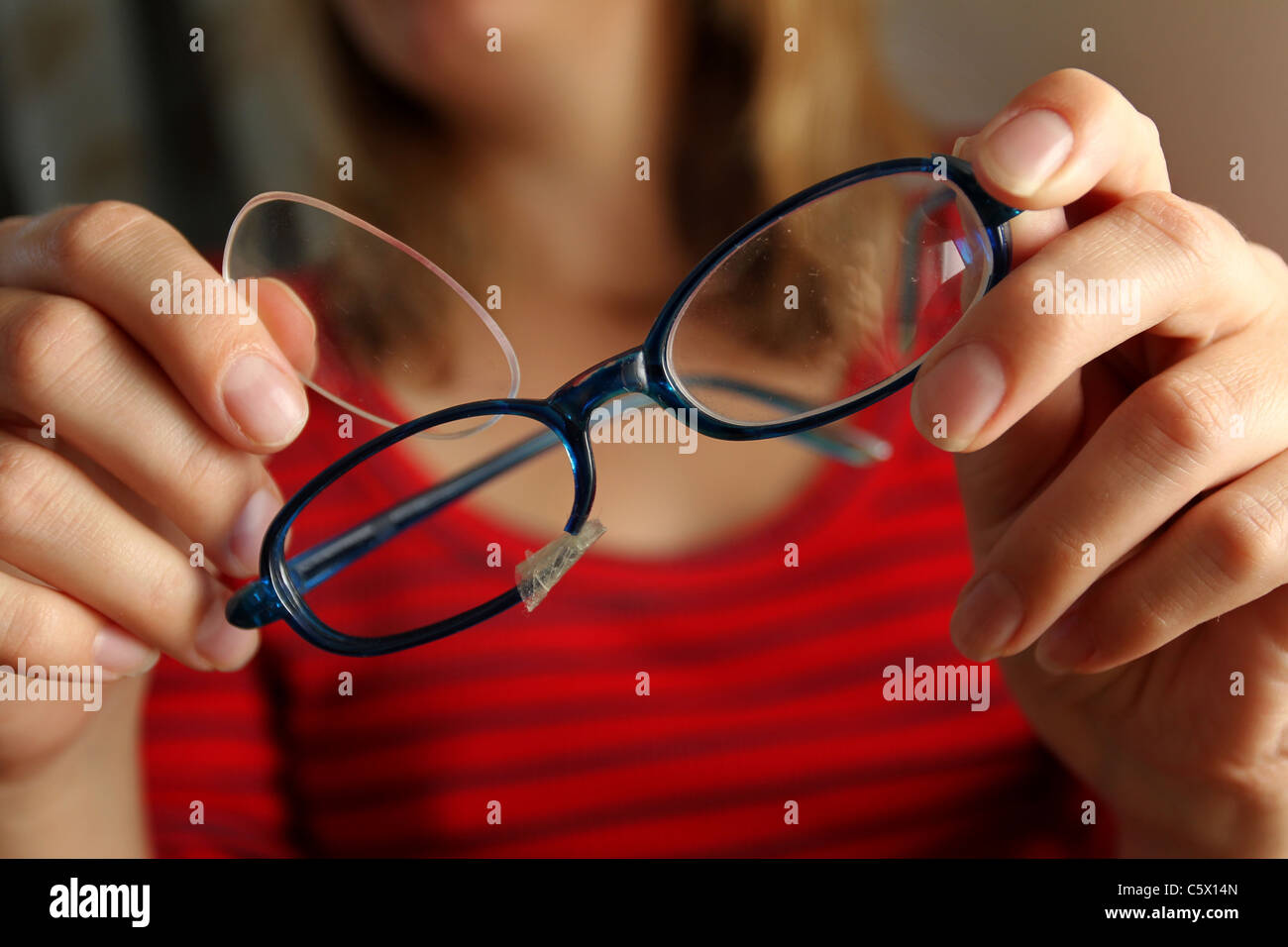 A young girl playing with her broken glasses in Hove, East Sussex, UK