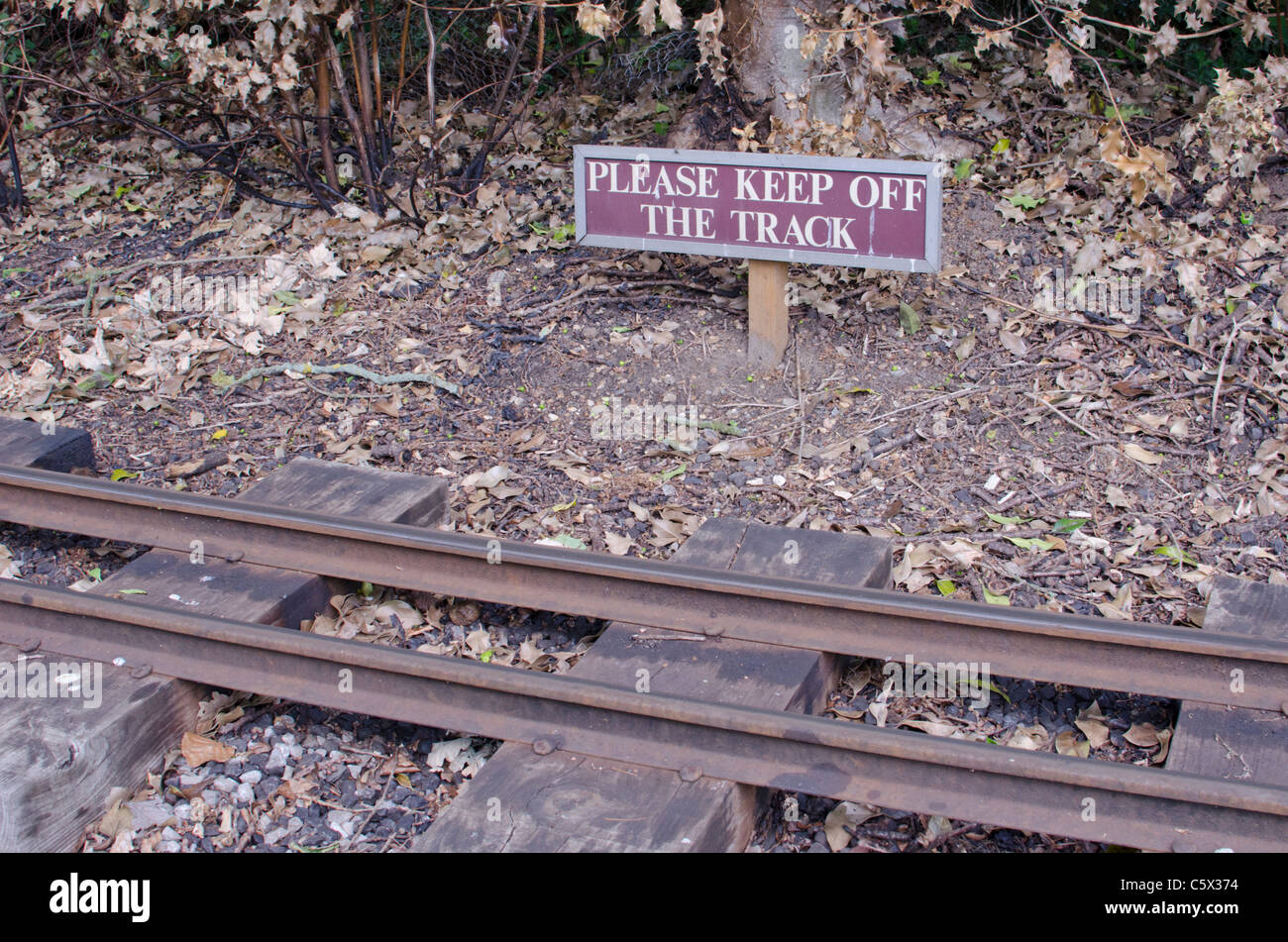 'Please keep off the track' sign beside a narrow-gauge steam railway line Stock Photo