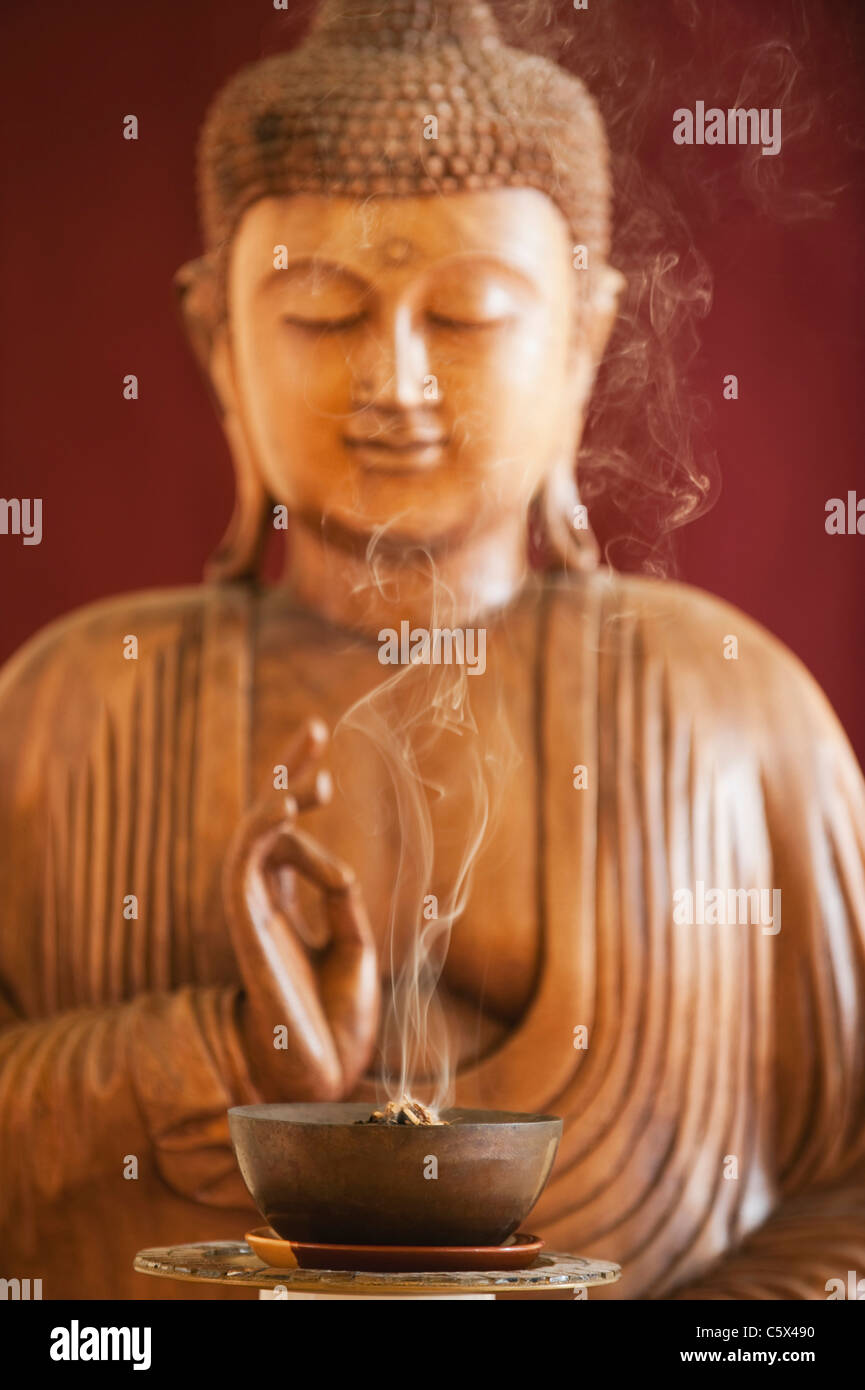 Buddha statue and a bowl with joss sticks Stock Photo Alamy