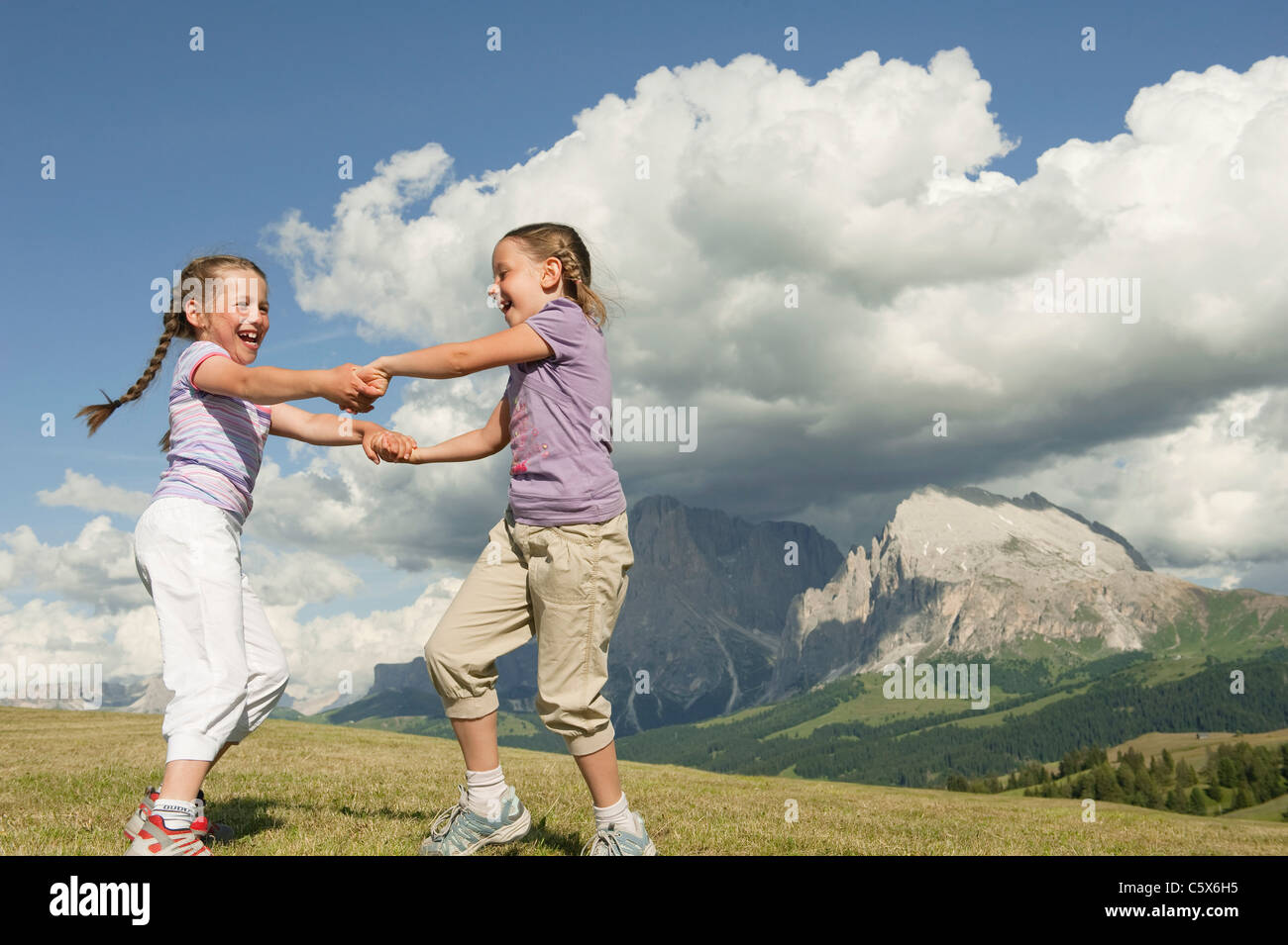Italy, Seiseralm, Girls (6-7), (8-9) dancing in meadow Stock Photo