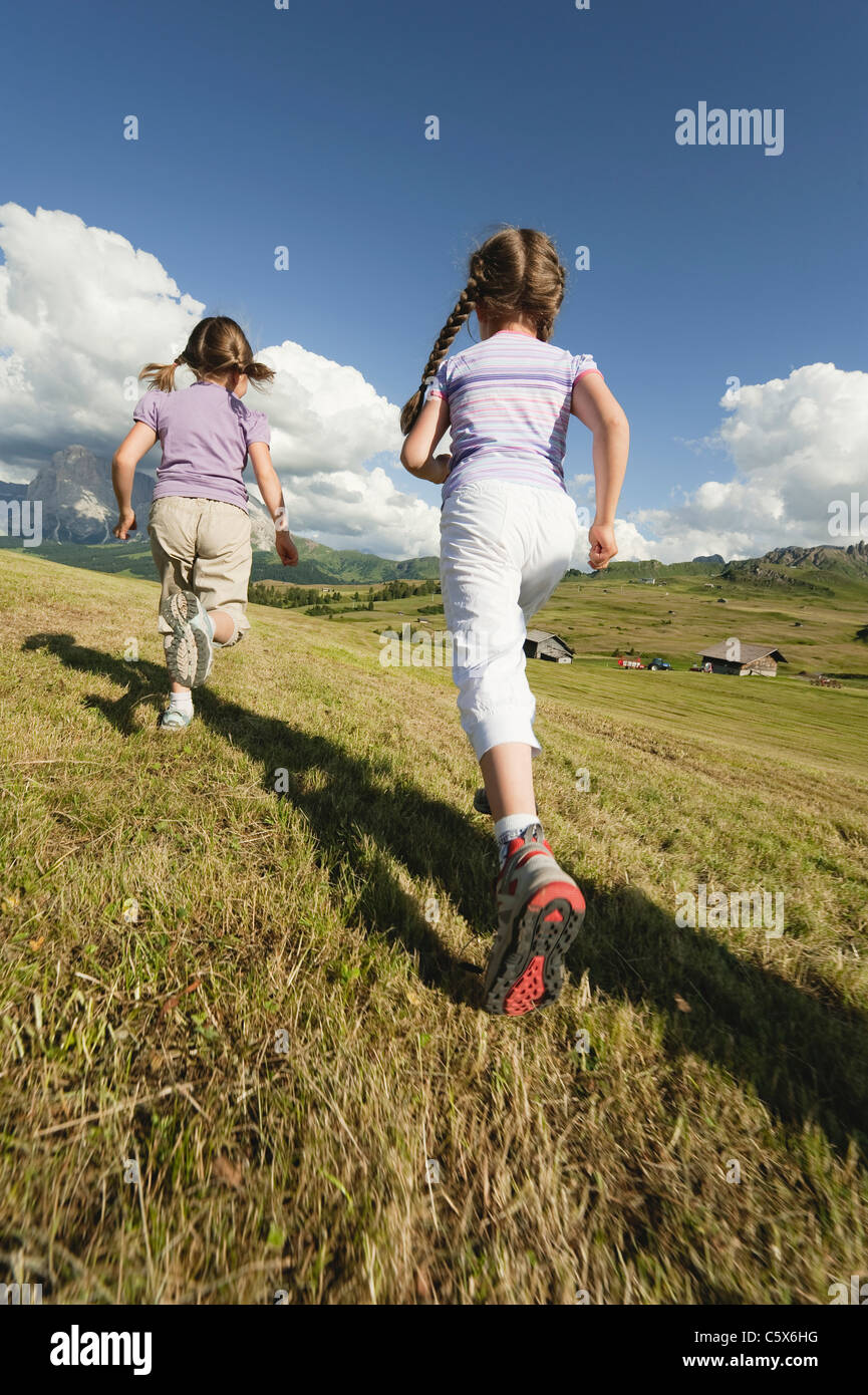 Italy, Seiseralm, Girls (6-7), (8-9) running in meadow, rear view Stock Photo