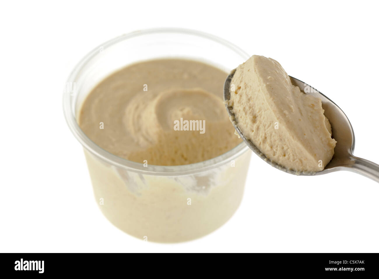 Clear opened tub of Houmous and a portion on a tablespoon Stock Photo