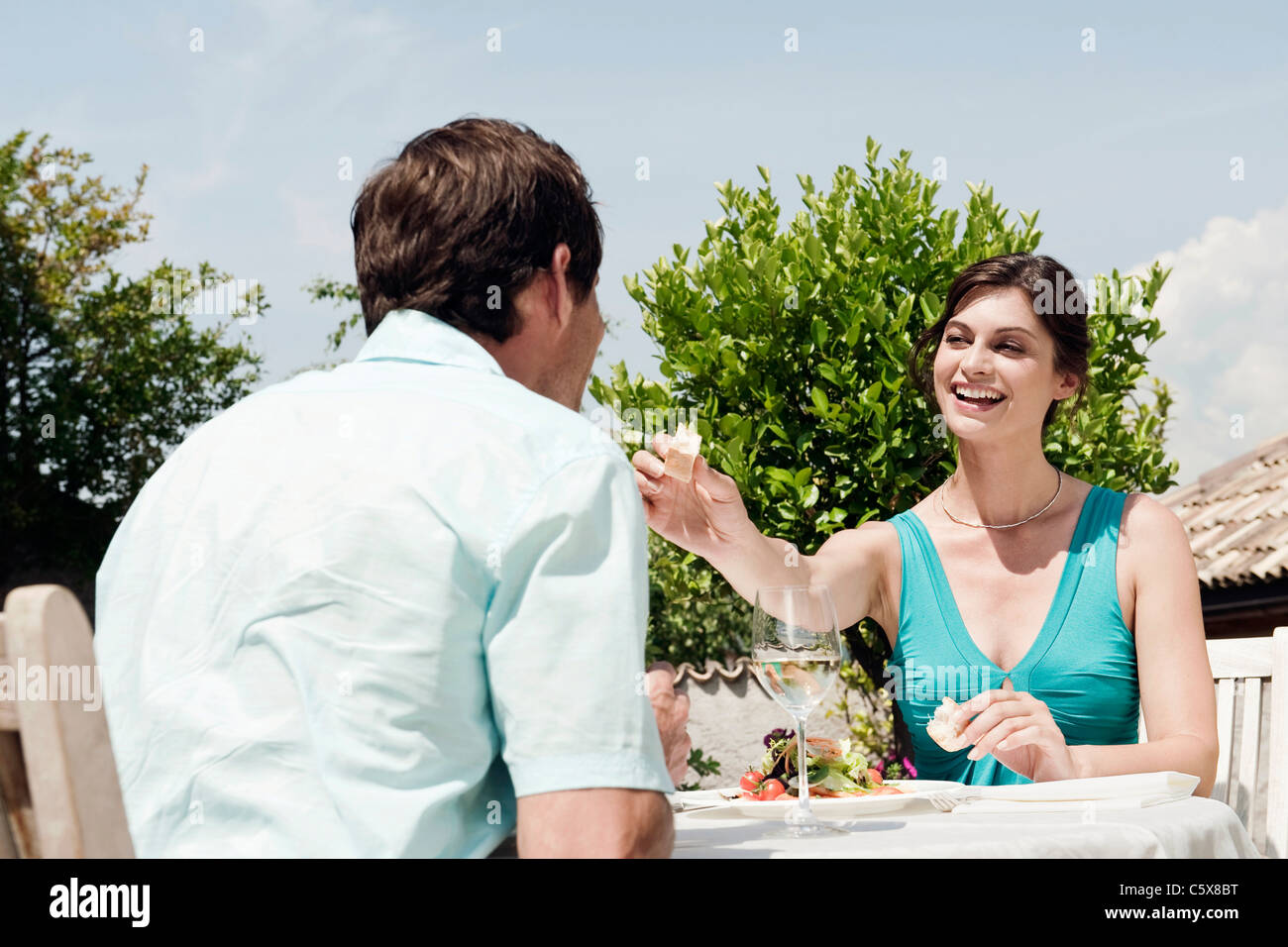 Italy, South Tyrol, Couple in restaurant, woman giving man a piece of bread Stock Photo
