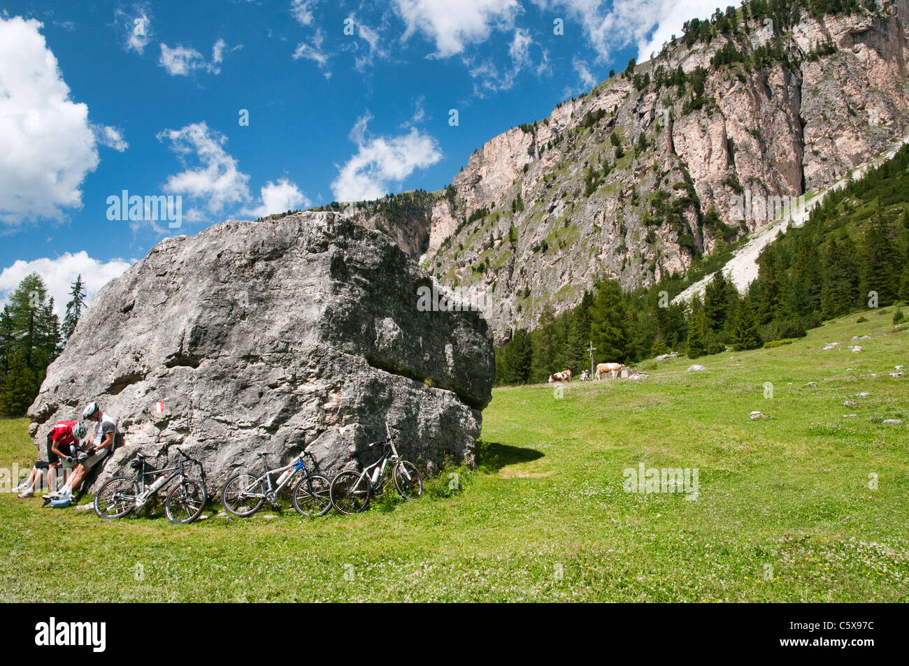 Cyclers resting in front of a big stone, South Tyrol Stock Photo