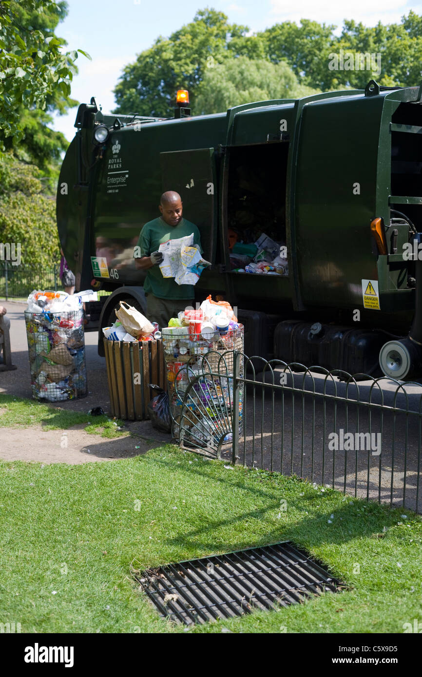 Dustman, emptying bins in a London park, pauses to read a map he has found in the rubbish Stock Photo