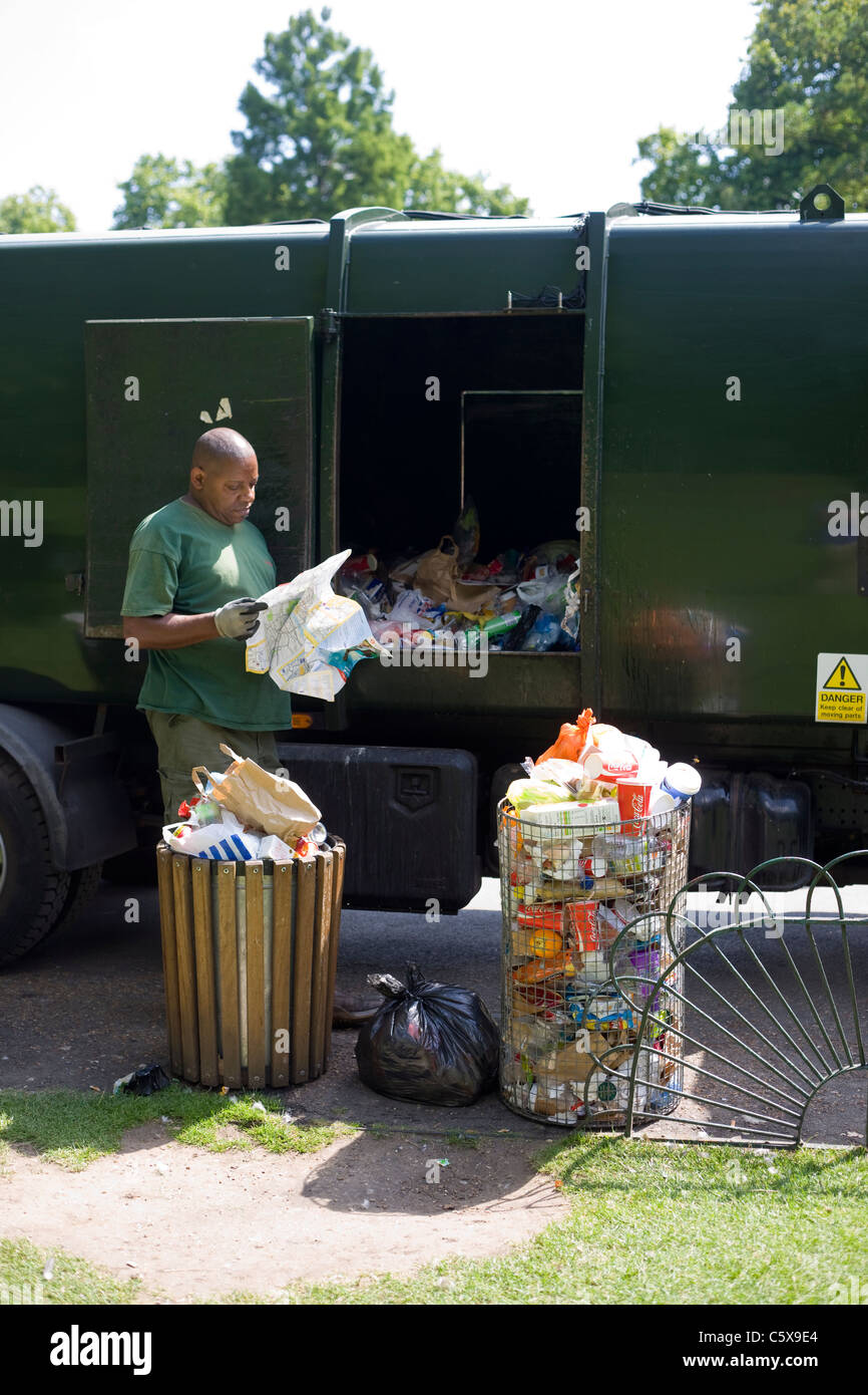 Dustman, emptying bins in a London park, pauses to read a map he has found in the rubbish Stock Photo
