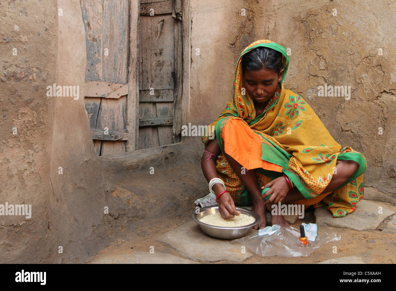 An Indian woman cleaning rice in front of her house Stock Photo Alamy