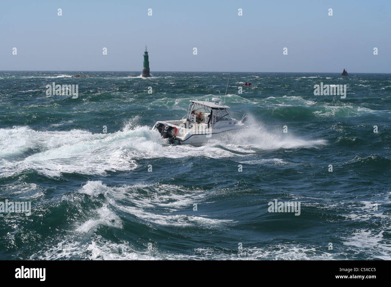 A pleasure boat sailing in rough seas, during departure of Tall ship's race, lighthouse 'Grand Jardin', St Malo (Brittany,France). Stock Photo