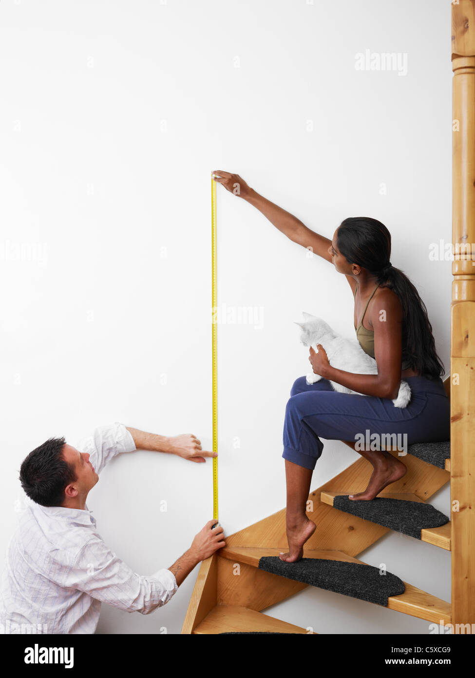 Do it yourself couple measuring wall to hang picture at home. Vertical