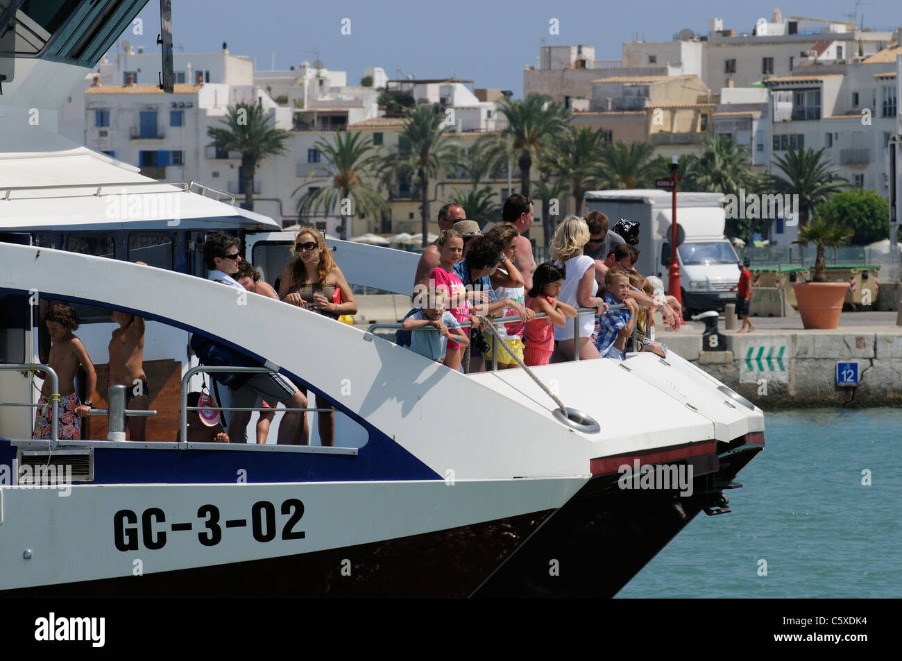 Ferry passengers standing on the bow of a fast ferry as it enters Eivissa Port on the Spanish island of Ibiza Stock Photo